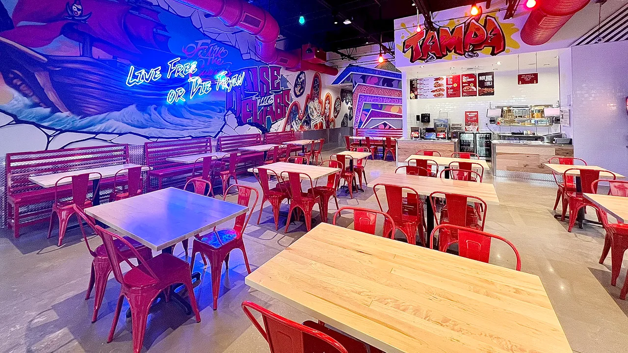 Interior view of seating and counter area at Dave's Hot Chicken on N Dale Mabry Hwy in Tampa, FL, featuring red chairs and colorful murals.