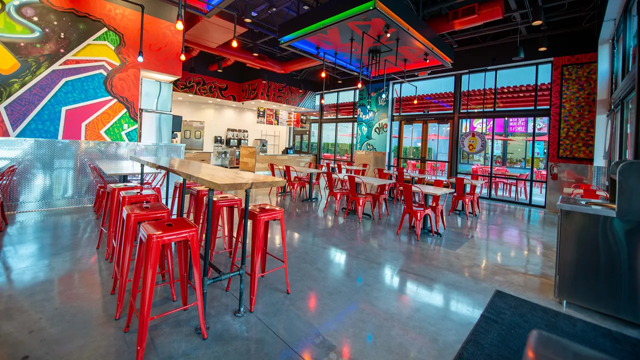 Spacious indoor seating area with red stools and tables inside Dave's Hot Chicken, NE 6th Ave, Vancouver, WA - Hazel Dell location.