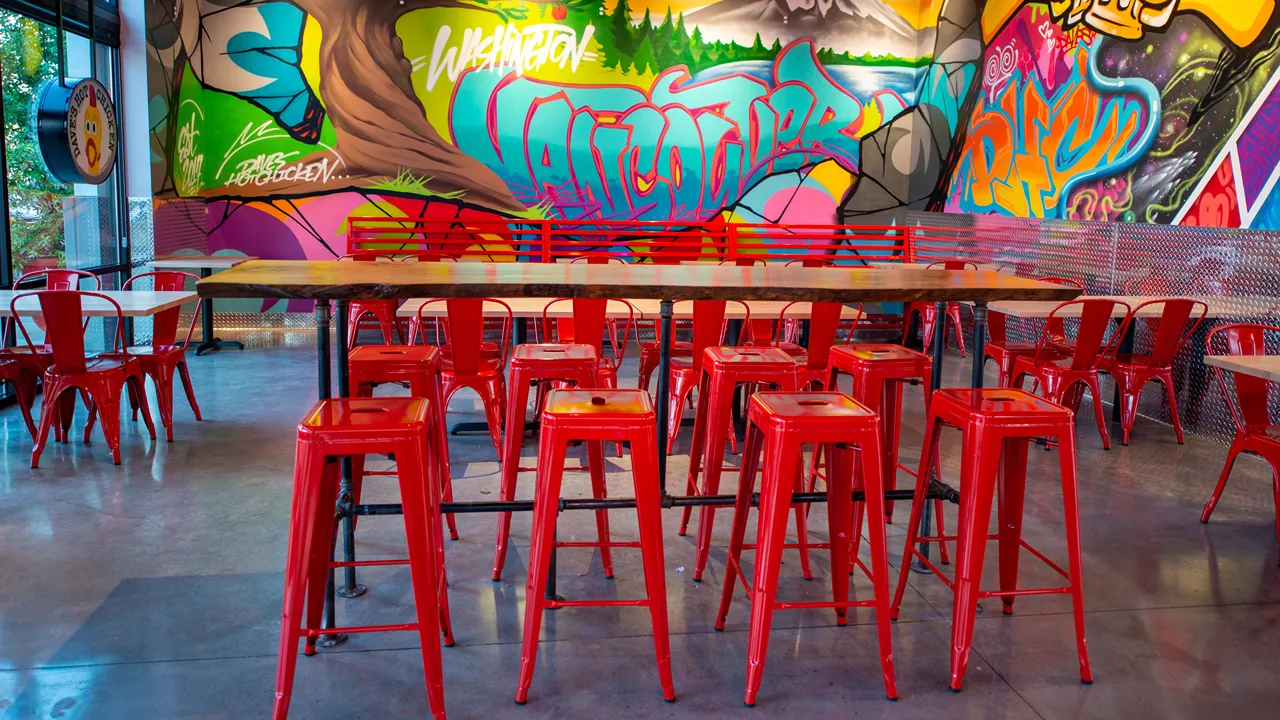 Interior seating arrangement with red chairs and colorful graffiti at Dave's Hot Chicken on NE 6th Ave, Vancouver, WA - Hazel Dell.