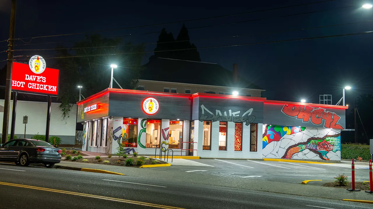 Exterior view of Dave's Hot Chicken on NE Sandy Blvd, Portland, OR, featuring the restaurant's signage and graffiti-style wall murals.