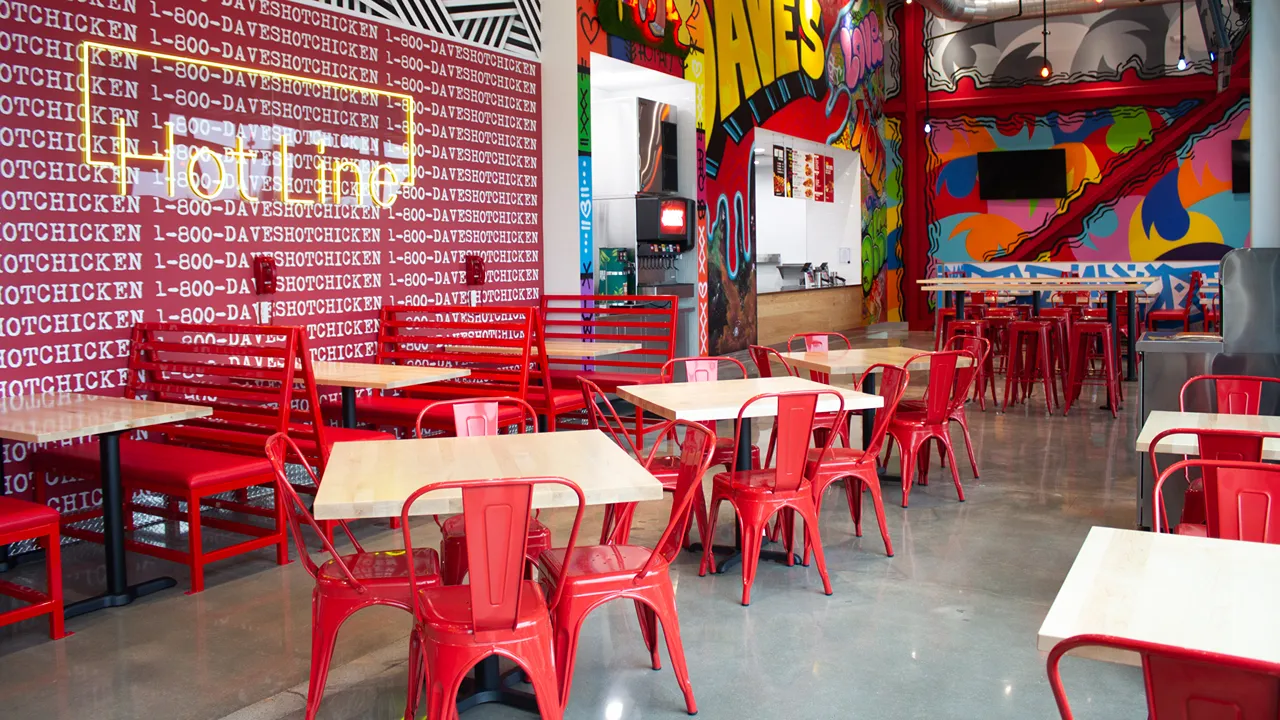 Red booths and seating with a 'Hotline' wall display at Dave's Hot Chicken in Chisholm Creek, Oklahoma City, OK.