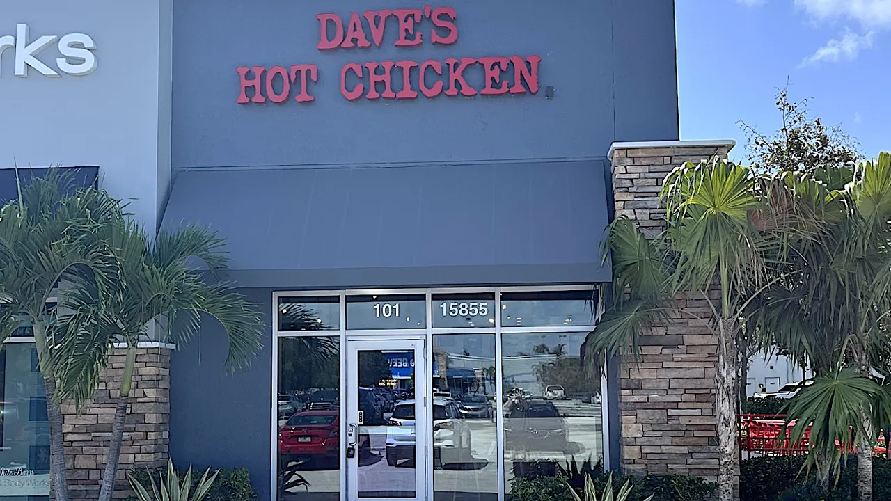 Exterior view of Dave’s Hot Chicken on Pines Blvd, Pembroke Pines, FL - West Fork, featuring palm trees and the storefront.