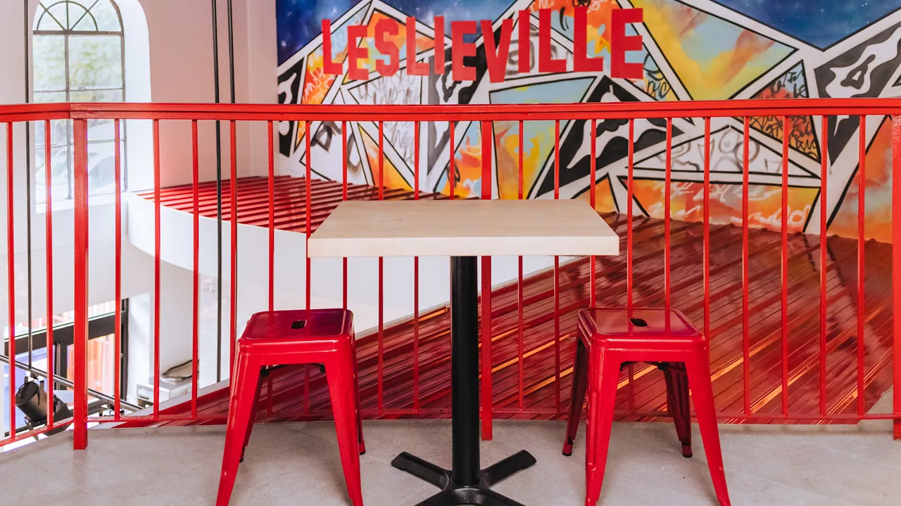 Interior of Dave's Hot Chicken in Leslieville, Toronto, ON, featuring red chairs and a Leslieville mural.