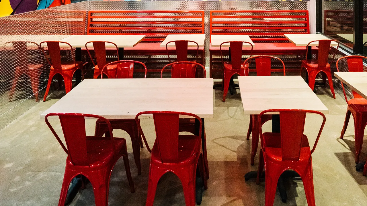 Wall art featuring vibrant graffiti with a seating area of red benches and tables inside Dave’s Hot Chicken on Reisterstown Rd, Owings Mills, MD.