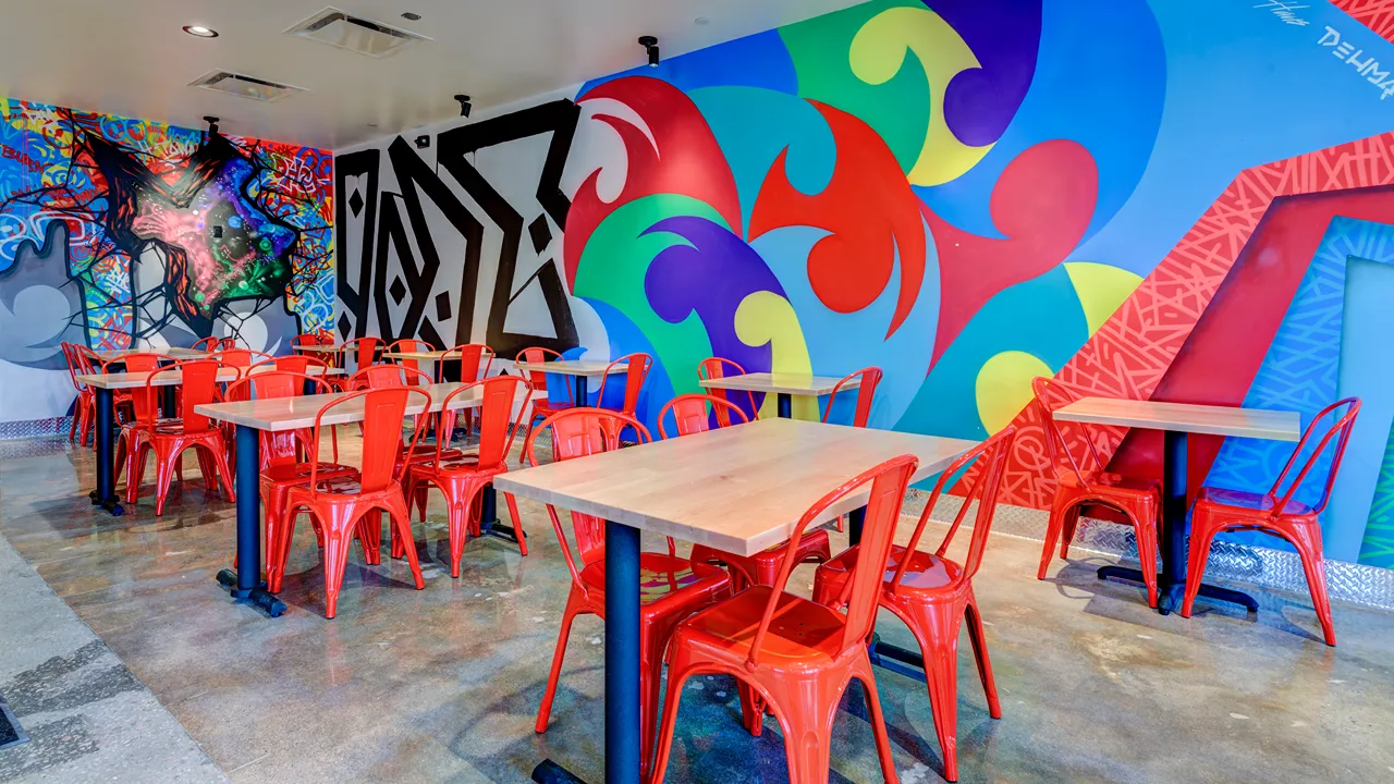 Interior mural with vibrant graffiti and red seating at Dave's Hot Chicken on Rice Blvd, Houston, TX.