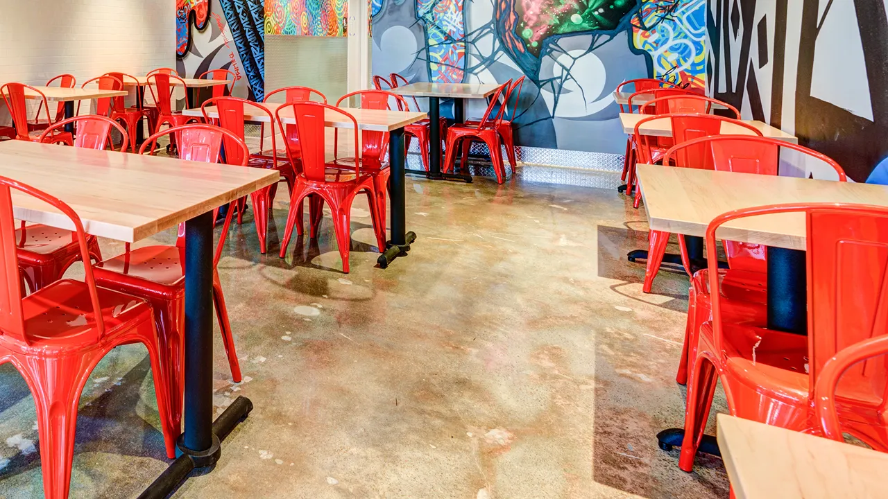 Interior seating area with red chairs and colorful wall murals at Dave's Hot Chicken on Rice Blvd, Houston, TX.