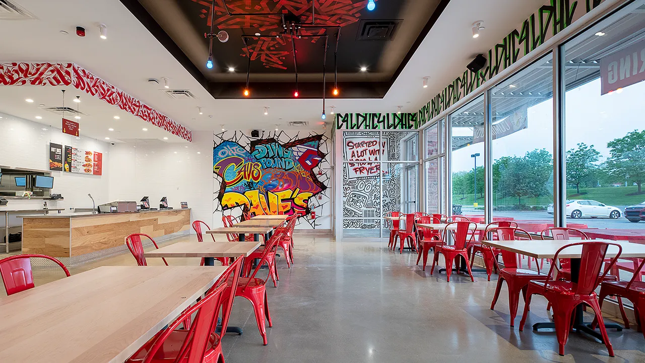 Interior view of Dave's Hot Chicken with bright red seating and murals on Richmond Rd, Warrensville Heights, OH.