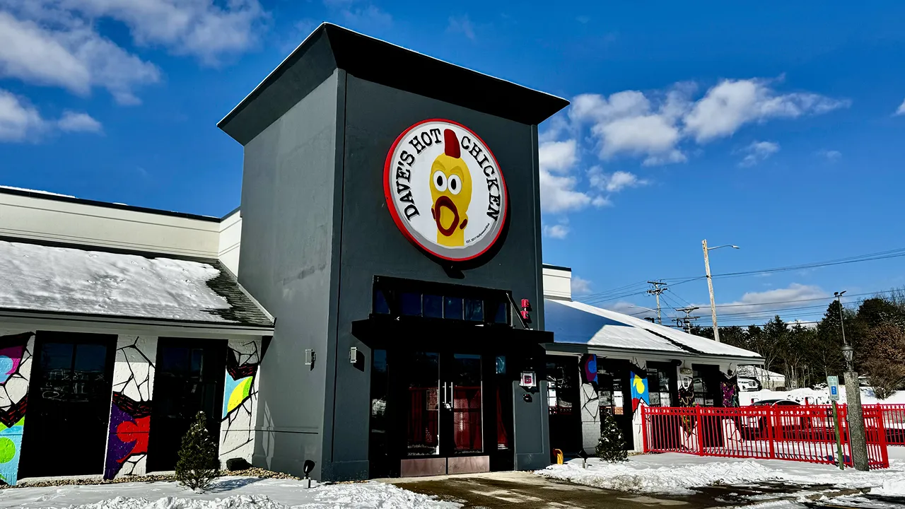 Exterior view of Dave's Hot Chicken on S. Willow St., Manchester, NH, with large signage and surrounding snow-covered ground.