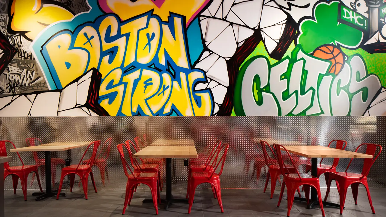 Interior mural at Dave's Hot Chicken on Stuart St in Boston, MA, at City Place, featuring bold 'Boston Strong' and 'Celtics' graffiti.