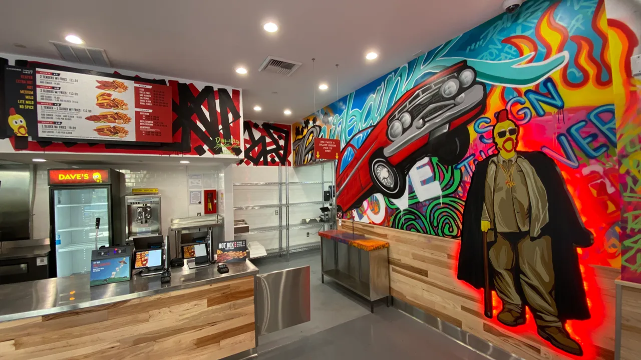 Interior of Dave's Hot Chicken in N Victory Pl, Burbank, CA, featuring graffiti art, a counter, and bold yellow lettering.