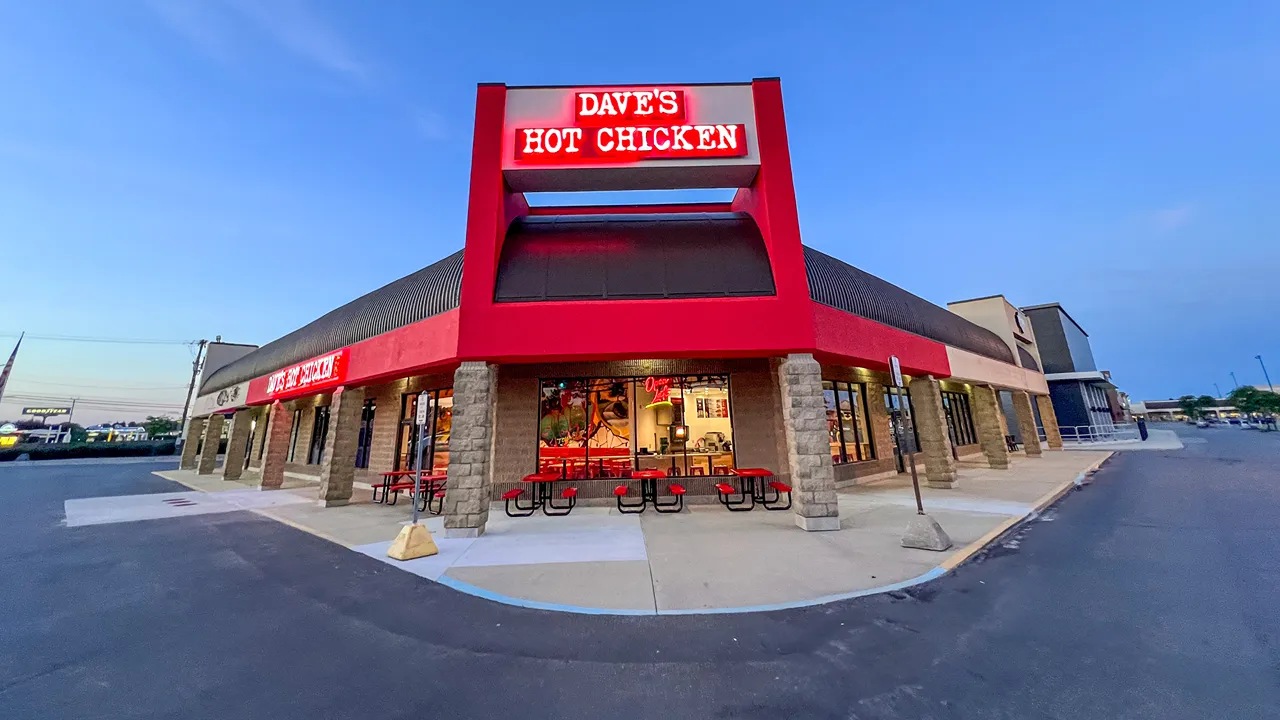 Exterior view of Dave's Hot Chicken at Hall Road, Shelby Township, MI, with red signage and outdoor seating.