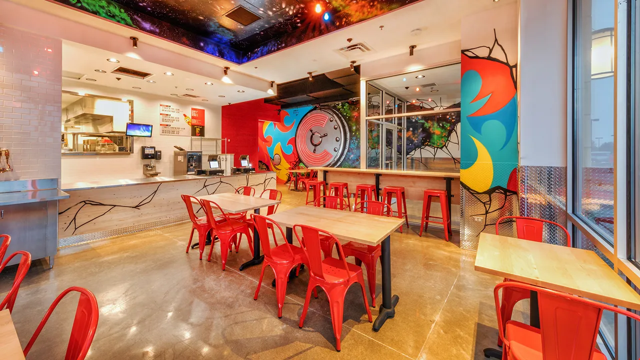 A wide-angle view of the dining area featuring murals, a counter, and seating at Dave's Hot Chicken on Showplace Dr., Naperville, IL.