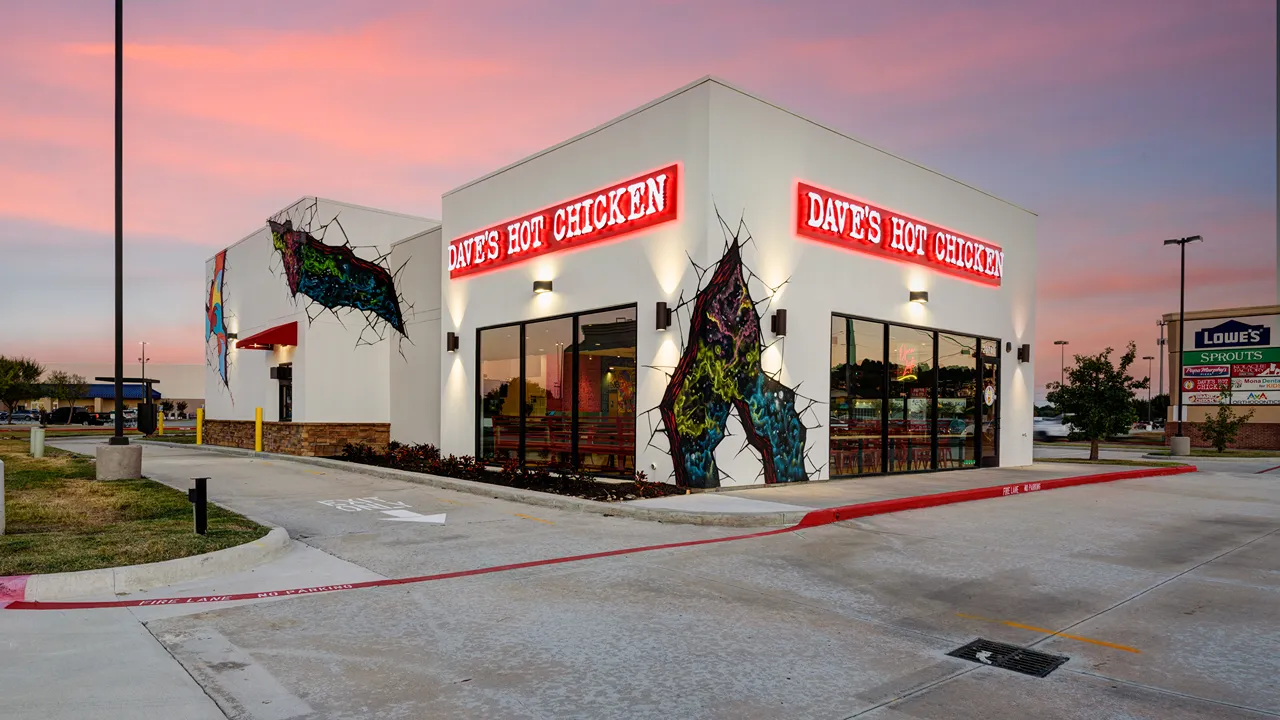 Evening exterior view of Dave's Hot Chicken location on Kuykendahl Road, Spring, TX, with bright signage and wall murals.