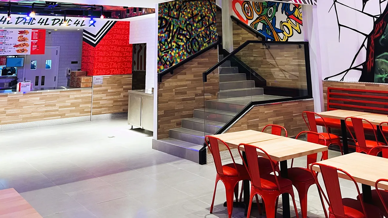 Interior seating and stairs with colorful wall art at Dave's Hot Chicken, Riyadh, located on Tahliah Street, Al Olaya.