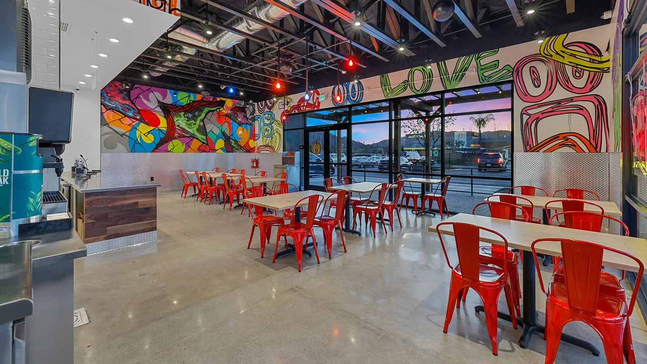 Interior of Dave's Hot Chicken on Temecula Pkwy, Temecula, CA, showing red chairs and colorful graffiti walls.