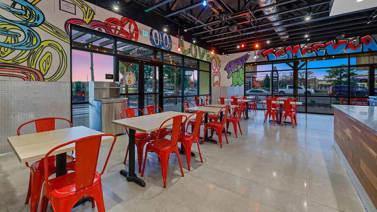 Dining area inside Dave's Hot Chicken on Temecula Pkwy, Temecula, CA, featuring large windows and red seating.