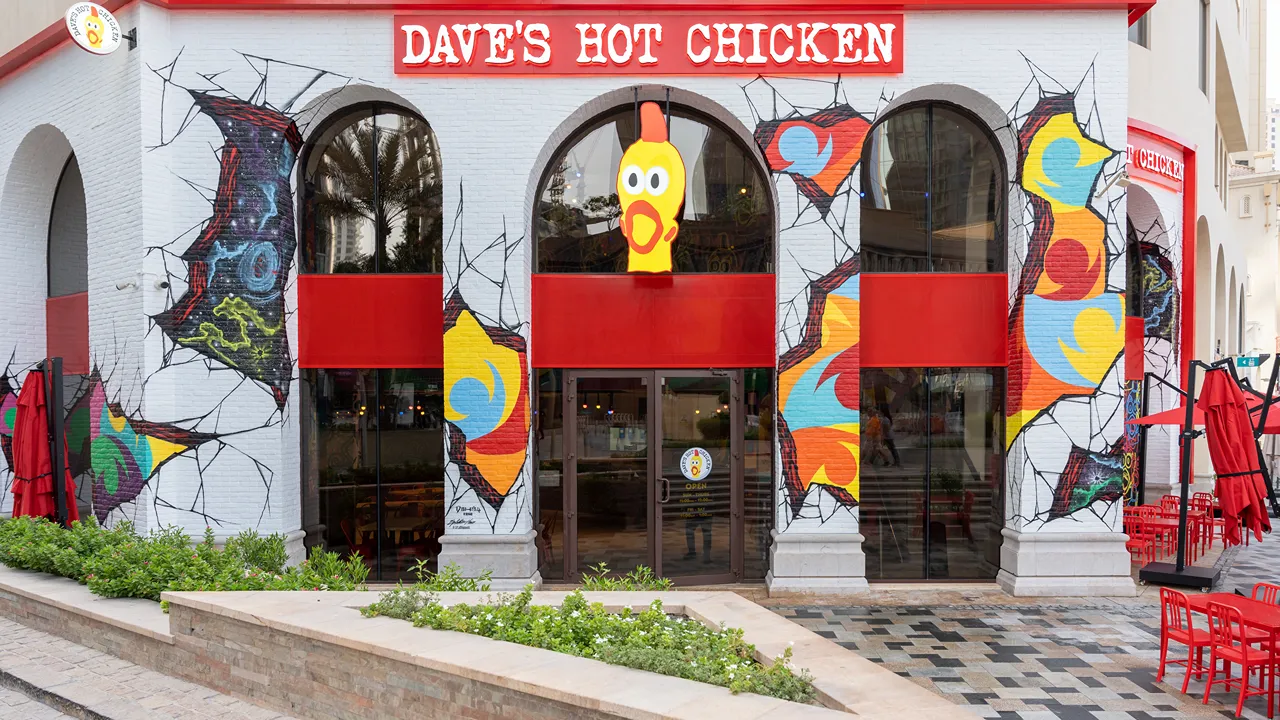 Exterior view of Dave's Hot Chicken with vibrant murals and arches at The Walk, Jumeirah Beach Residence in Dubai, UAE.