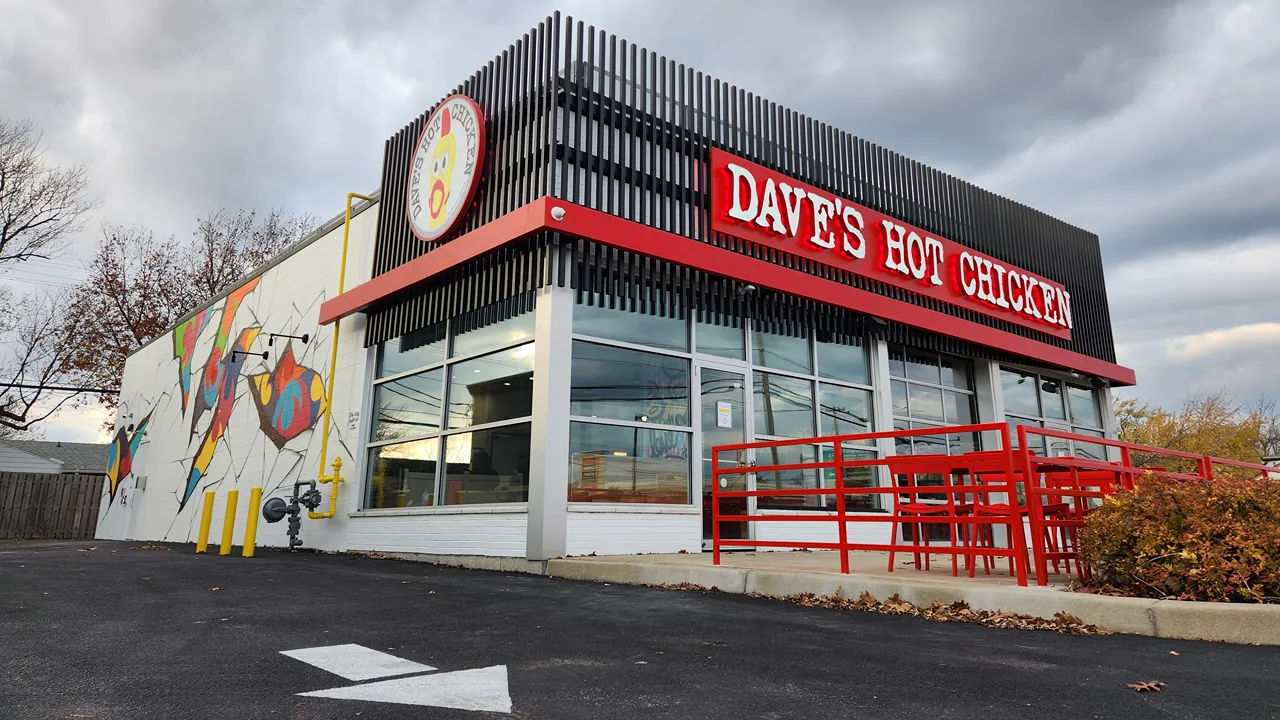 Side view of Dave's Hot Chicken in Tonawanda, NY, near Buffalo, with a clear shot of the building's vibrant wall art and outdoor seating area.