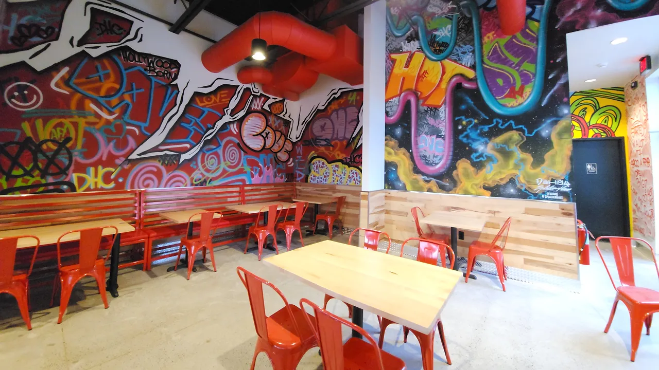 Seating area inside Dave's Hot Chicken, Tonawanda, NY, near Buffalo, with red chairs and graffiti-style wall art adding a vibrant touch.