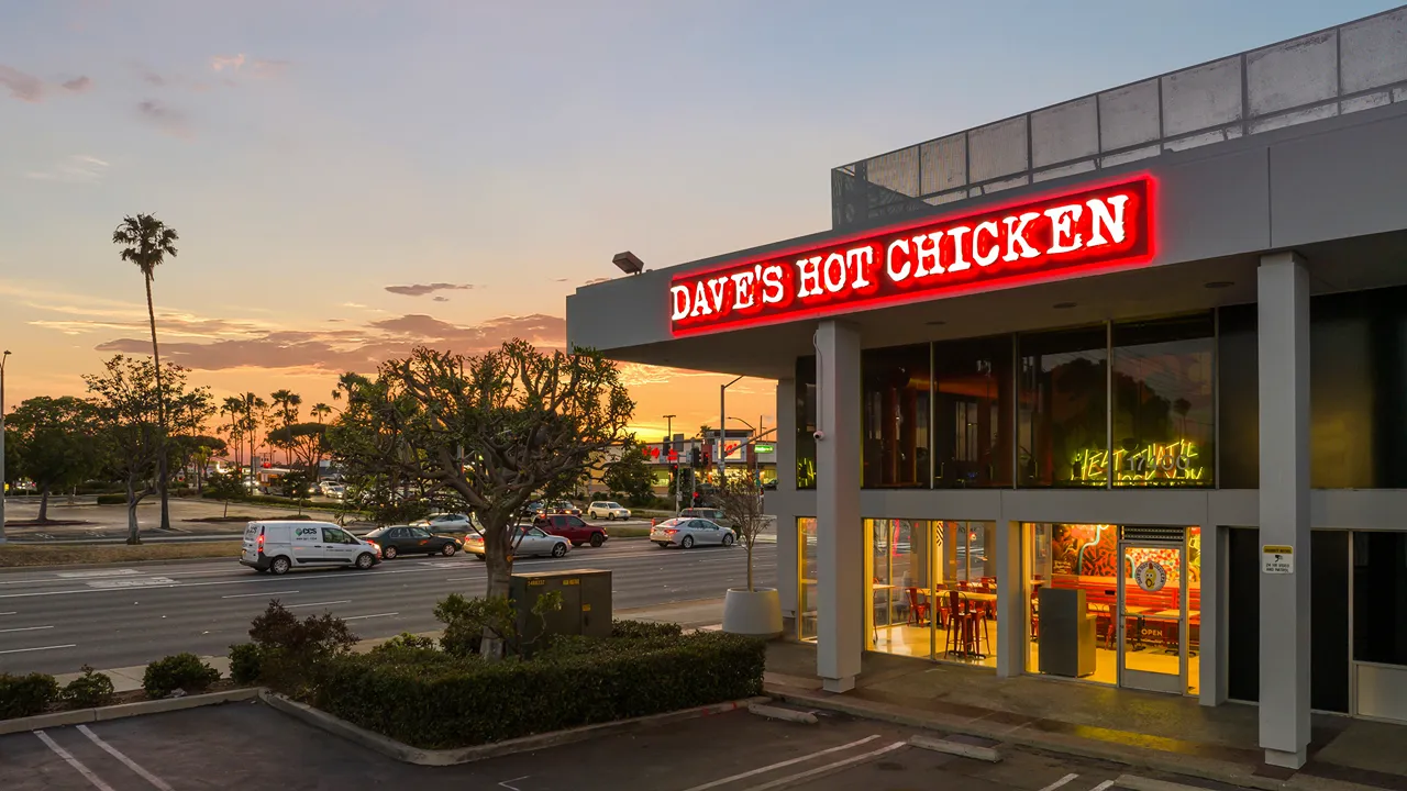 Exterior night view of Dave's Hot Chicken on Hawthorne Blvd, Torrance, CA, with bright neon signage and well-lit windows.