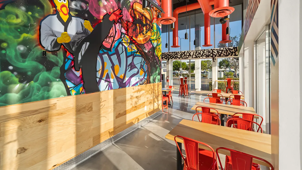 Interior view of Dave's Hot Chicken on Hawthorne Blvd, Torrance, CA, showcasing bold wall art and red seating area.