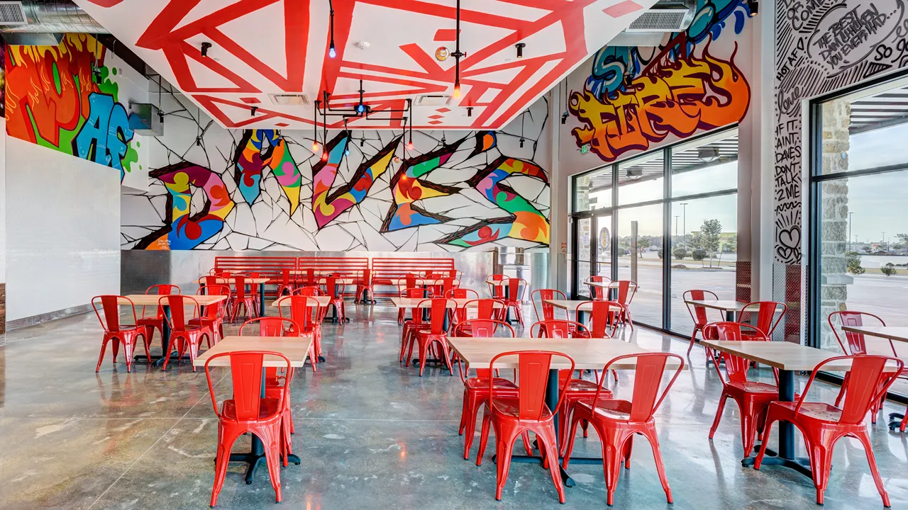 Dining area with wall murals and red chairs at Dave’s Hot Chicken, US Hwy 59, Valley Ranch, New Caney, TX.