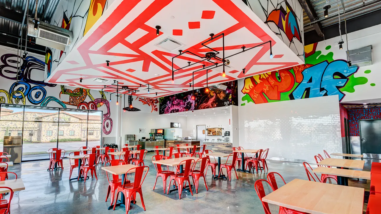 Bright dining area with colorful ceiling murals and red seating at Dave’s Hot Chicken, US Hwy 59, Valley Ranch, New Caney, TX.