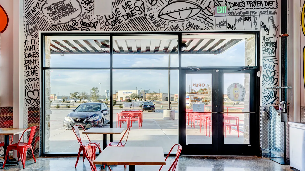 Indoor view with wall murals and window seating at Dave’s Hot Chicken, US Hwy 59, Valley Ranch, New Caney, TX.