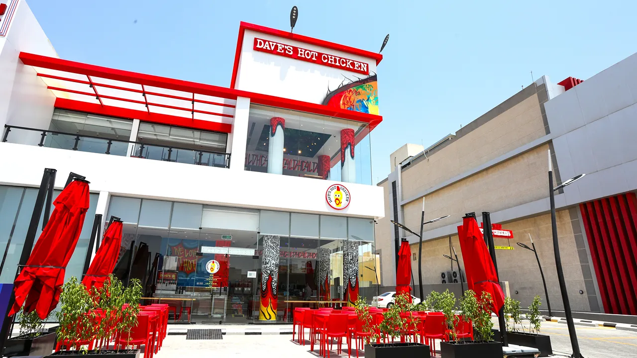 Exterior view of Dave's Hot Chicken on Uthman Ibn Affan Branch Rd, Riyadh, KSA, with outdoor seating and bold signage.