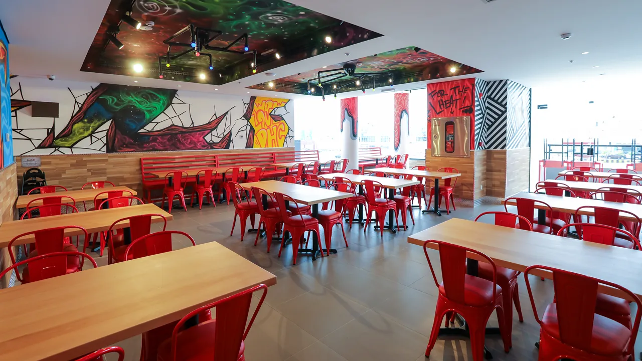 Interior seating area at Dave's Hot Chicken, Riyadh, KSA, with red chairs and artistic graffiti walls