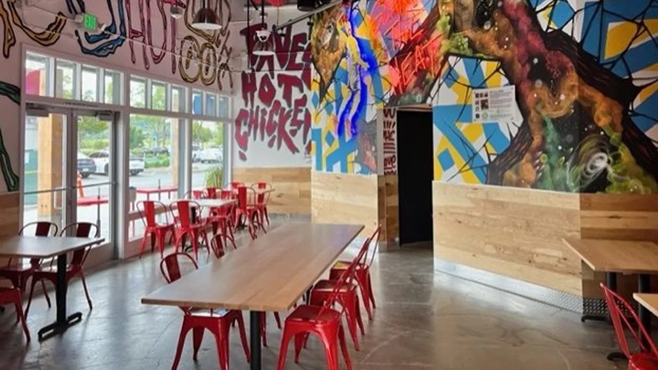 Dining area with red chairs, vibrant murals, and neon art at Dave's Hot Chicken on Vintage Way, Novato, CA.