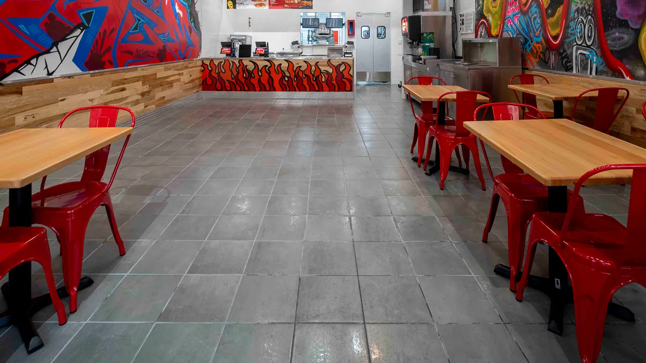 A long view of the restaurant seating area and counter with colorful wall murals at Dave’s Hot Chicken, W. 125th St., Harlem, New York, NY.