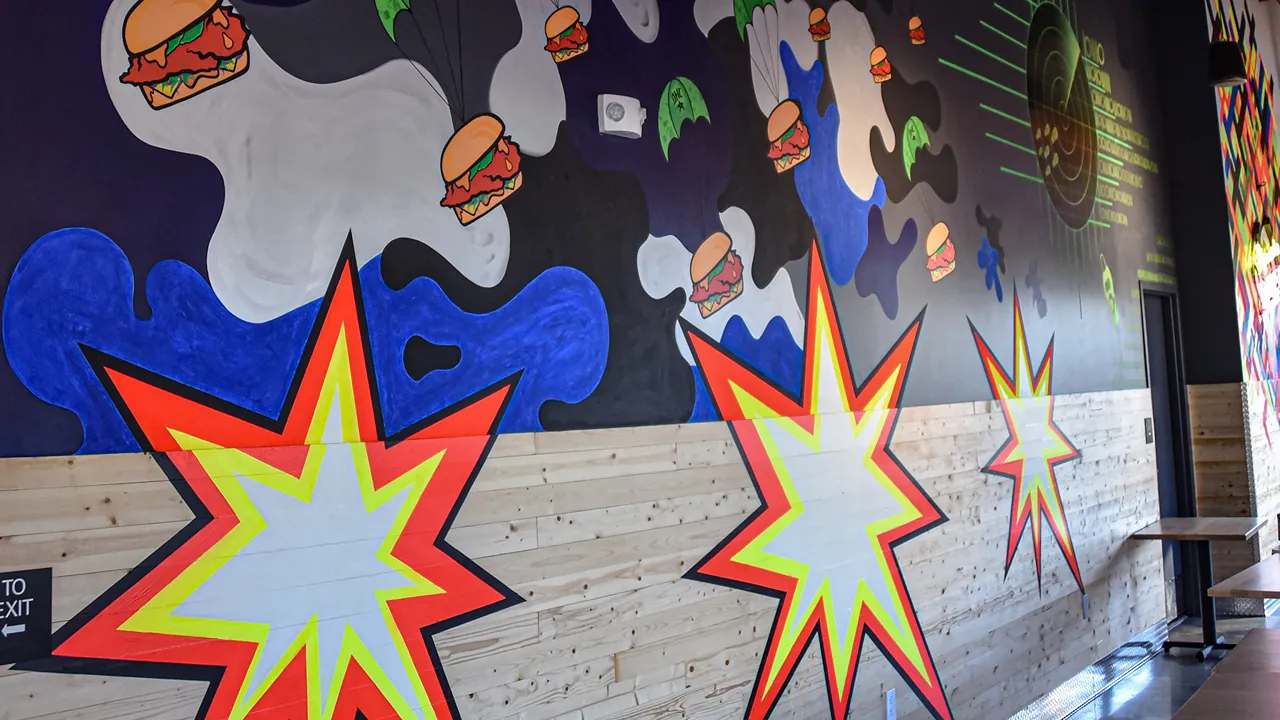 Large mural with bold burger-themed illustrations inside Dave’s Hot Chicken on W. Channel Islands Blvd, Port Hueneme, CA.