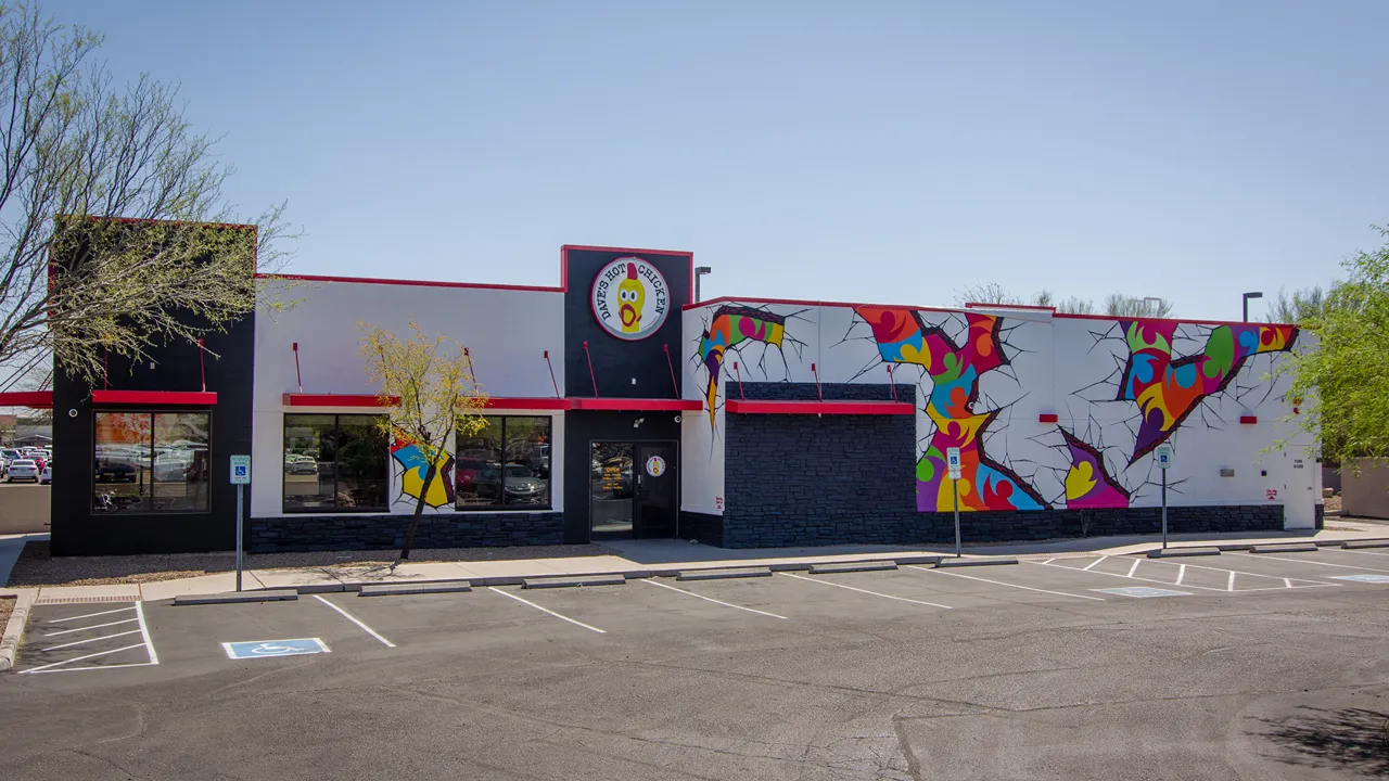 Exterior view of the Dave's Hot Chicken building on W. Costco Dr, Marana, AZ, with artistic murals and bold branding.