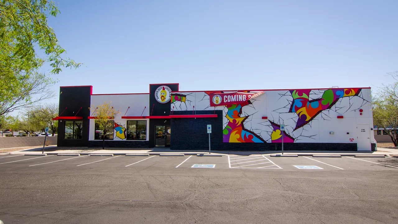 Wide view of the Dave's Hot Chicken building on W. Costco Dr, Marana, AZ, with artistic murals and bold branding.