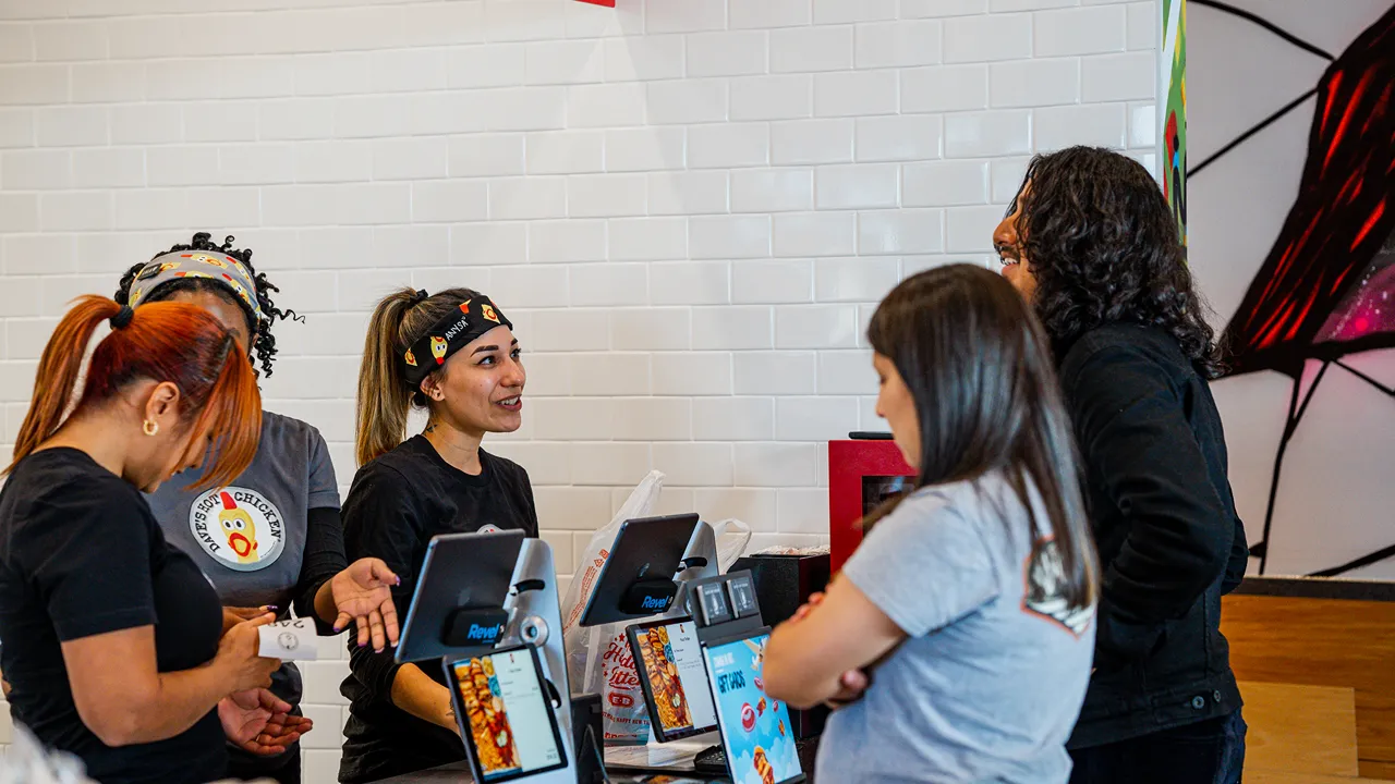 Interior view of Dave's Hot Chicken on W. Expressway 83, McAllen, TX, showing staff assisting customers at the counter with a tiled backdrop.