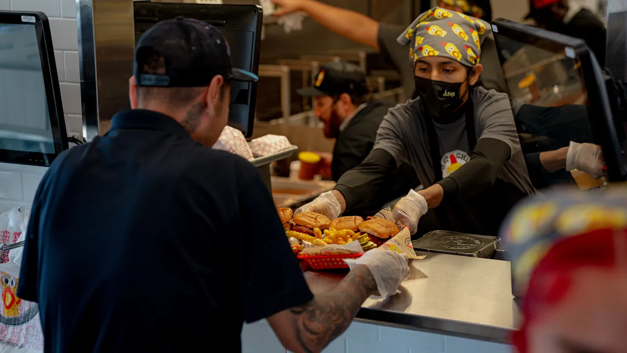 Close-up of the kitchen serving area at Dave's Hot Chicken on W. Expressway 83, McAllen, TX, with staff handing out fresh meals.