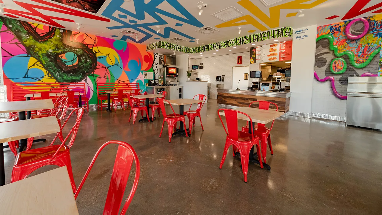 Interior of Dave's Hot Chicken in Waco, TX on Jack Kultgen Fwy, featuring the service counter and dining area with red chairs.