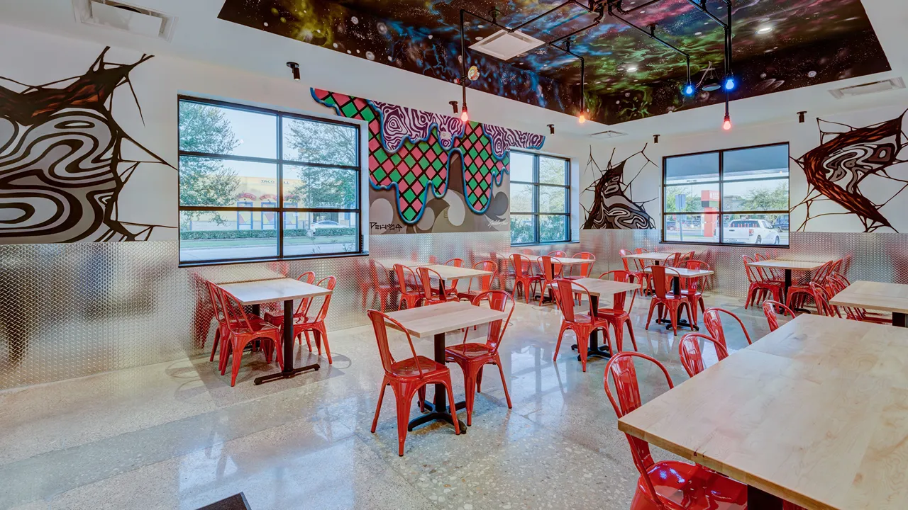 Interior dining room with colorful murals and red seating at Dave's Hot Chicken on Wallisville Rd, Houston, TX.