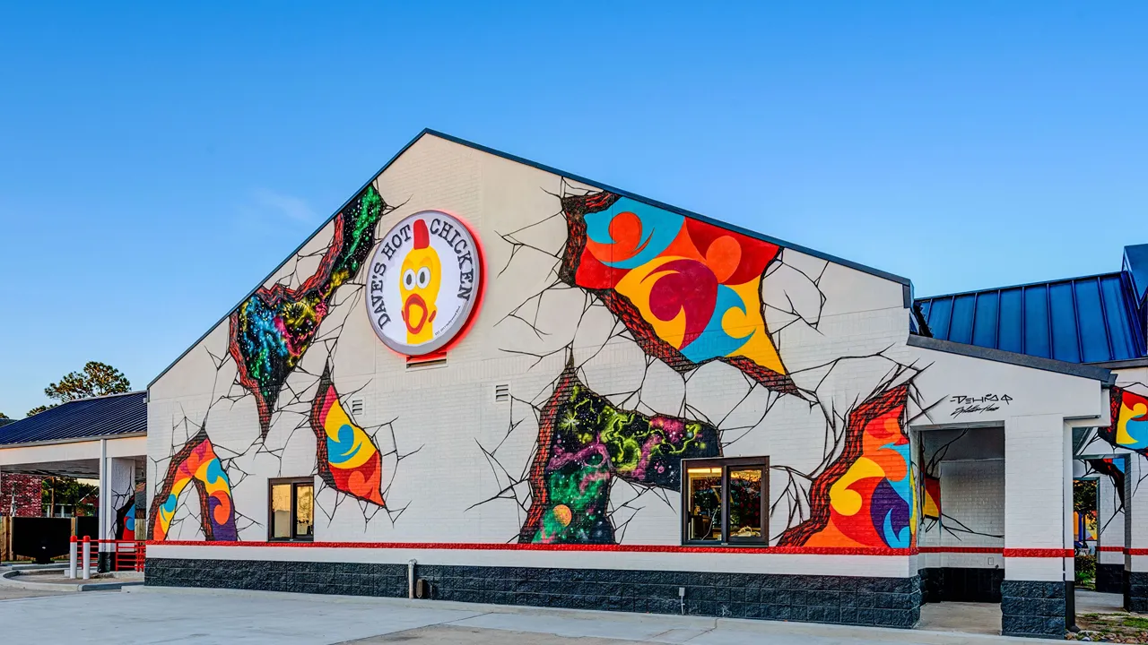 Exterior view of Dave's Hot Chicken with vibrant wall murals and signage at Wallisville Rd, Houston, TX.