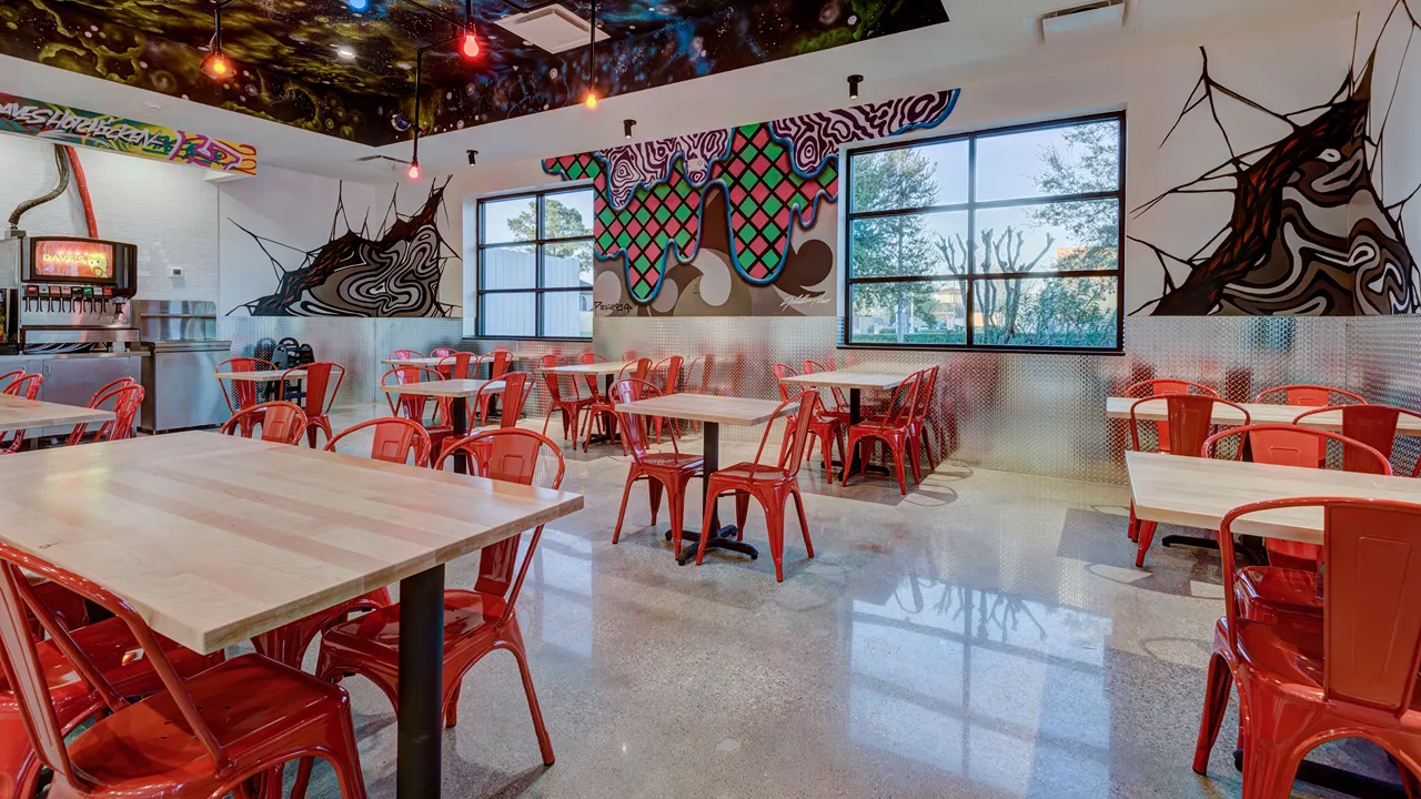 Interior seating area with red chairs and unique wall art at Dave's Hot Chicken on Wallisville Rd, Houston, TX.