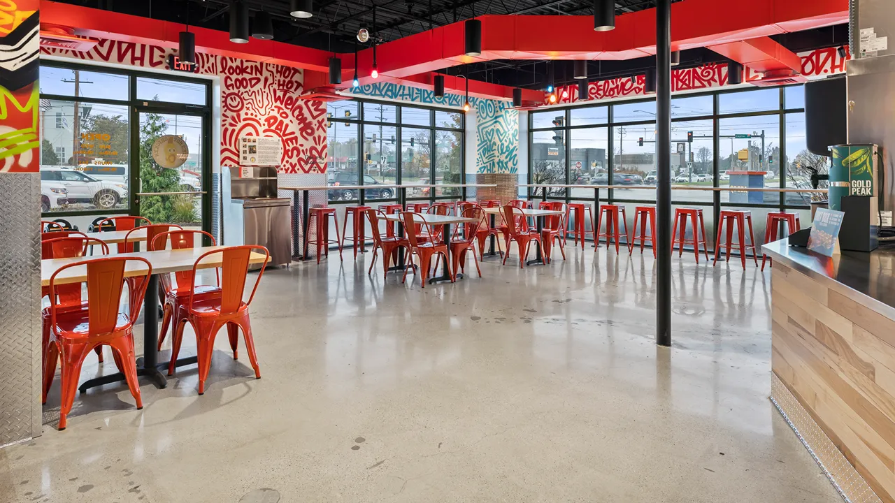 Spacious dining area with red chairs and vibrant wall art at Dave’s Hot Chicken on Capitol Dr in Wauwatosa, WI.