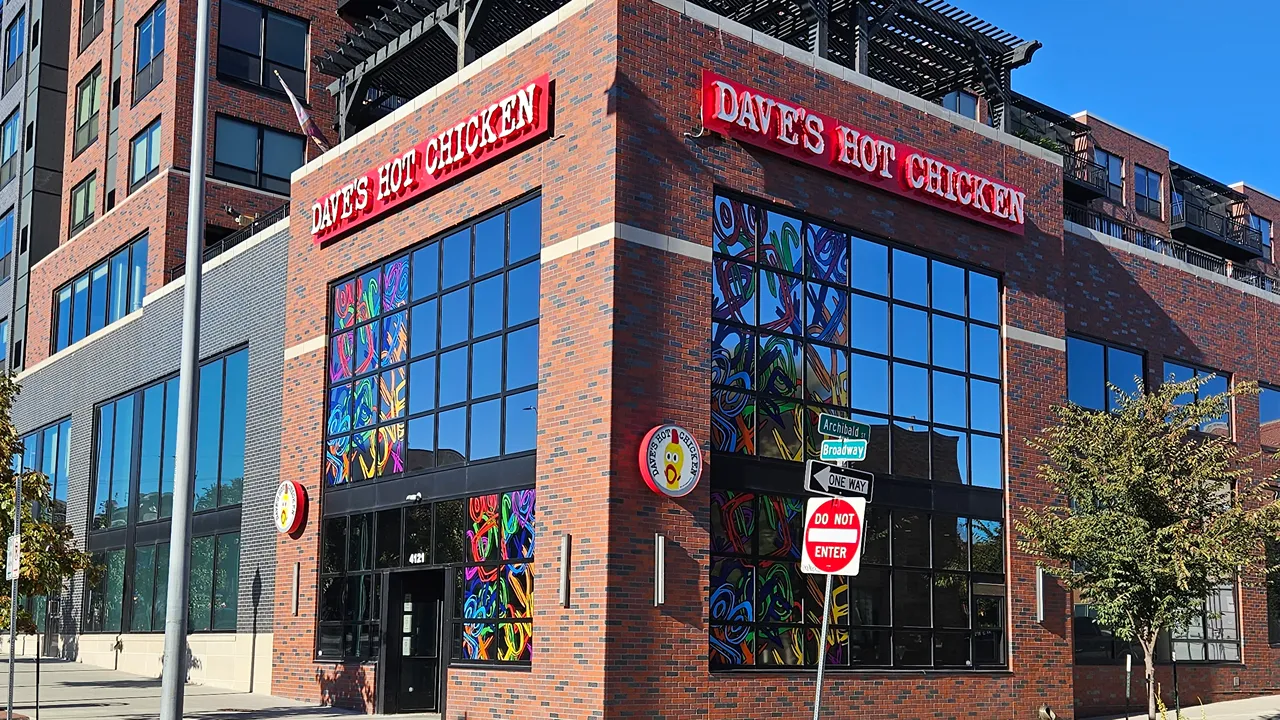 Exterior view of Dave’s Hot Chicken at Westley on Broadway, Kansas City, MO, featuring vibrant murals and large windows.