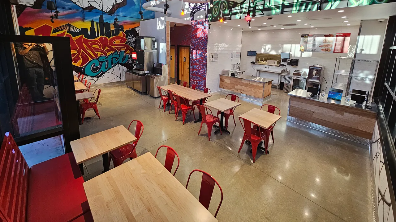 Interior view of Dave's Hot Chicken, Westley on Broadway, Kansas City, MO, showcasing red seating and vibrant wall art.