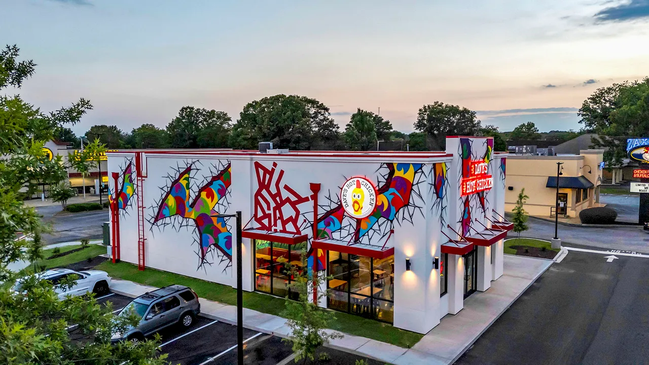 Modern exterior of Dave’s Hot Chicken in Greenville, SC on Woodruff Road, featuring bold murals and signature red signage.