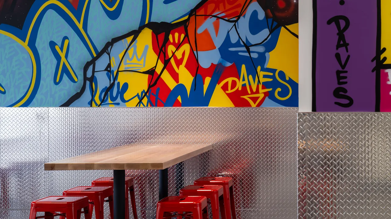 Mural-covered wall with seating arrangement inside Dave's Hot Chicken on Yonge & Dundas, Toronto, ON.