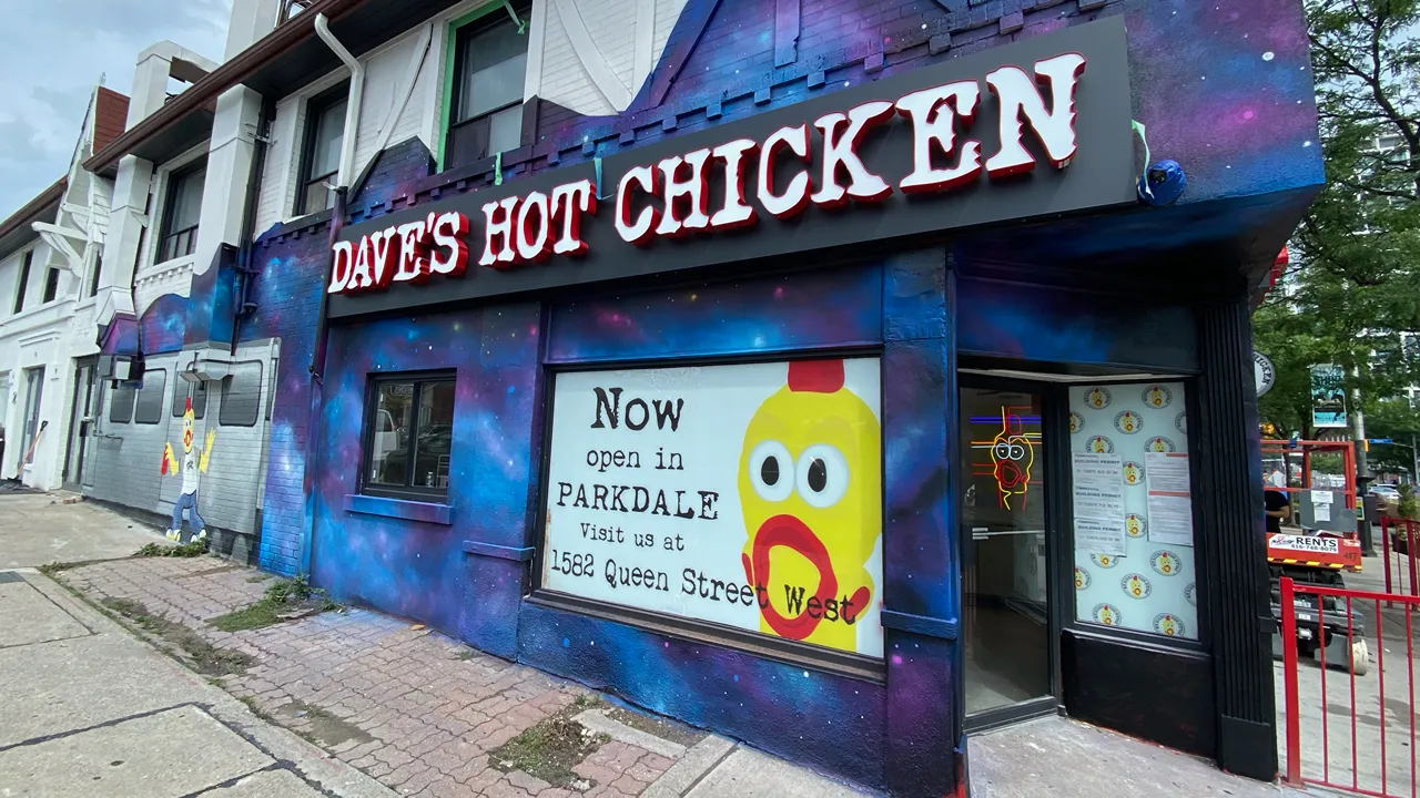 Exterior view of Dave's Hot Chicken restaurant on Yonge Street, Midtown, Toronto, ON, featuring vibrant street art and red signage.