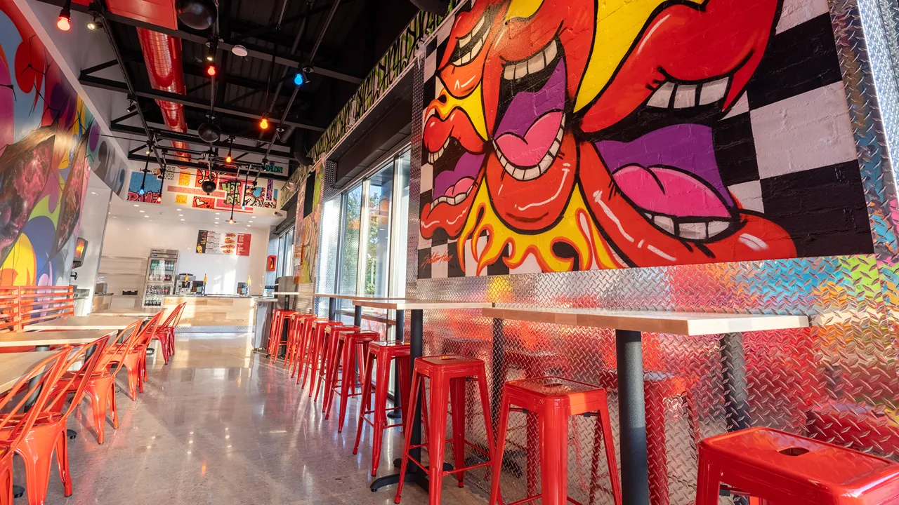 Bar seating area with red stools along a colorful wall at Dave's Hot Chicken, 1300 The Plaza, near Central Avenue, Charlotte, NC.