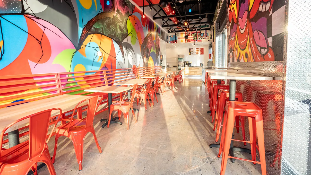 Indoor seating area with vibrant murals and red chairs at Dave's Hot Chicken, 1300 The Plaza, near Central Avenue, Charlotte, NC.