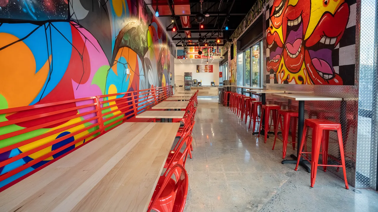 Seating area with red chairs and vibrant wall art at Dave's Hot Chicken, 1300 The Plaza, near Central Avenue in Plaza Midwood, Charlotte, NC.